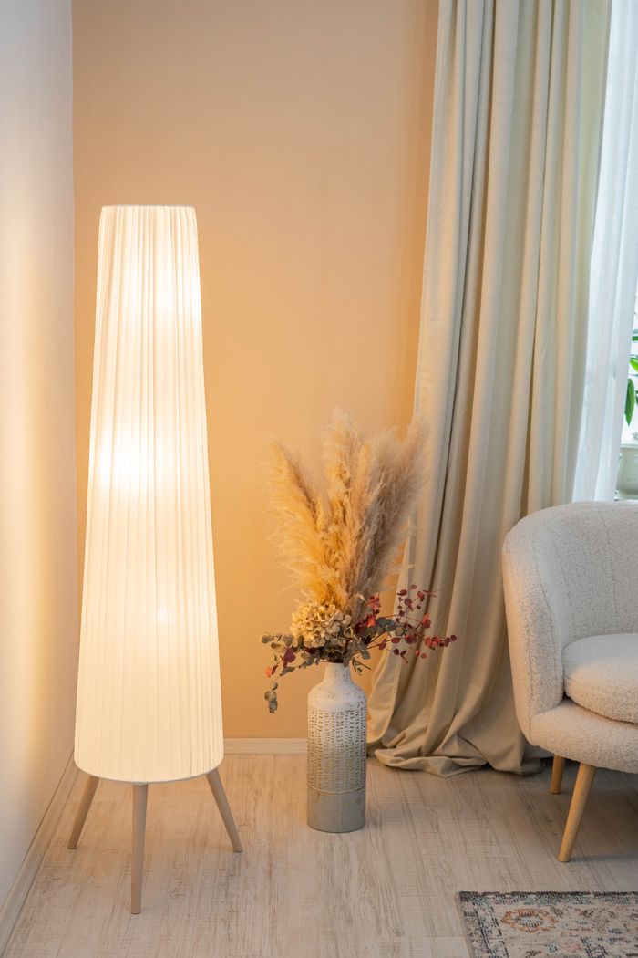 Elegant living room corner featuring a tall lamp, dried flowers, and a comfy chair in Constanța, Romania.
